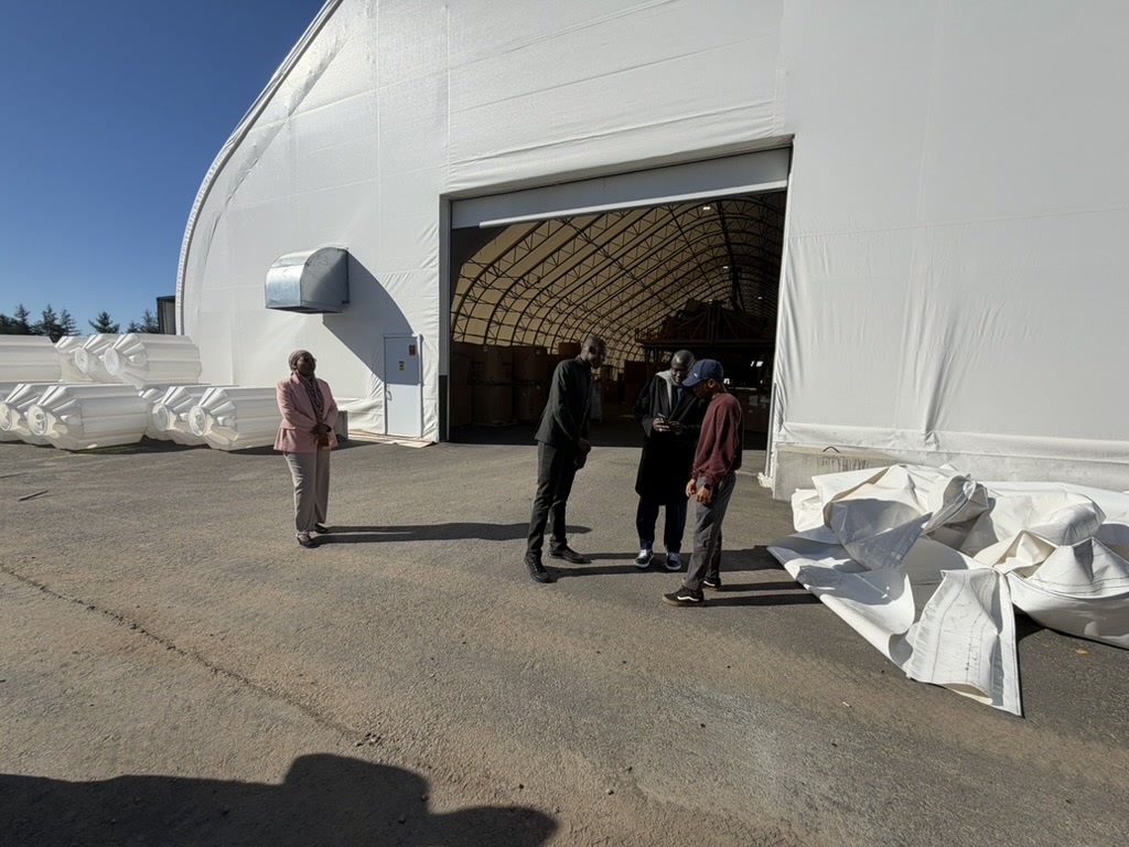 Visiteurs devant la grande porte ouverte de l’atelier